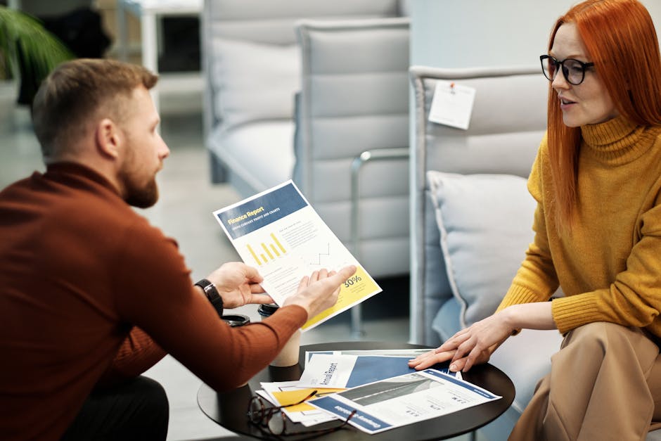 Two B2B sales professionals in a focused 1:1 conversation at a conference networking lounge
