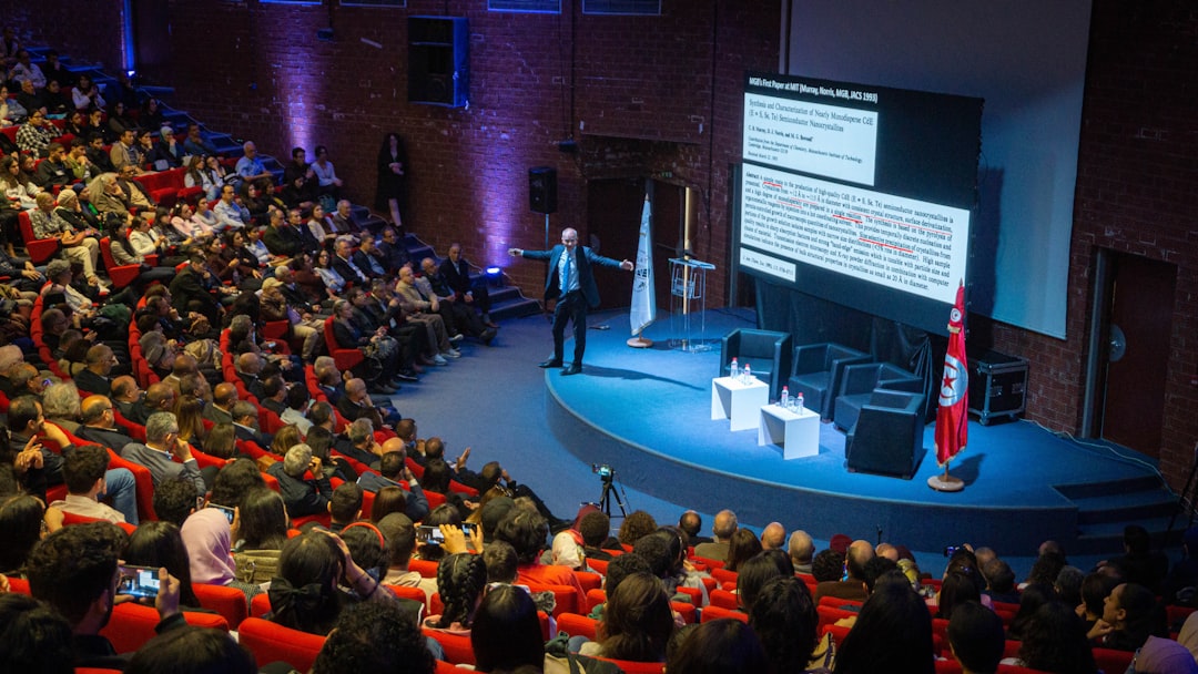 Packed auditorium of delegates seated facing a stage, illustrating events still built around sessions not connection