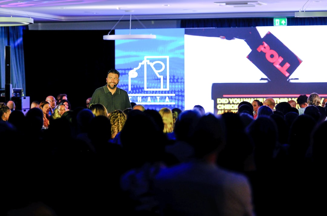 Wide view of a packed tech summit audience where young professional loneliness sits hidden inside the crowd of delegates